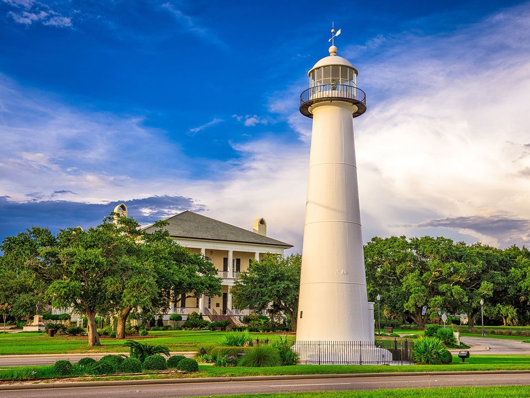 The Biloxi Lighthouse and the grounds behind it under a dramatic evening sky